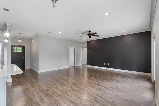 a view of an empty room with wooden floor and a chandelier