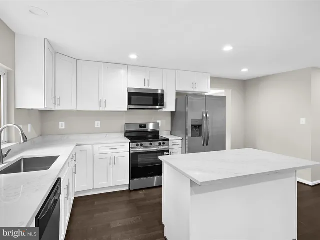 a kitchen with a sink a stove a refrigerator a center island and cabinets