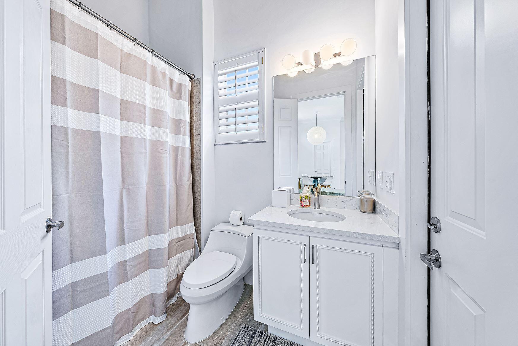 102 Via Santa Cruz Jupiter, FL 33458 - Photo 14 of 30 a bathroom with a sink a toilet a mirror and shower curtain