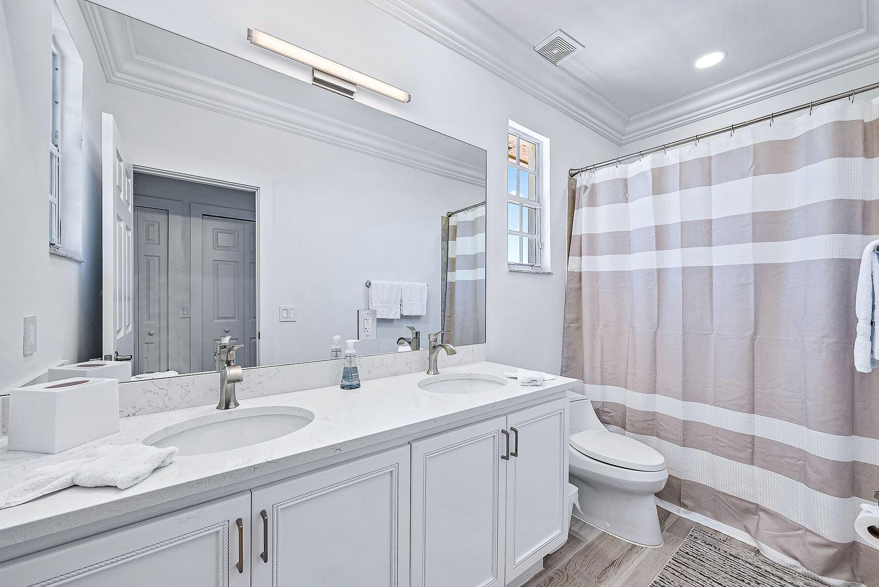 102 Via Santa Cruz Jupiter, FL 33458 - Photo 26 of 30 a bathroom with a double vanity sink toilet and a mirror