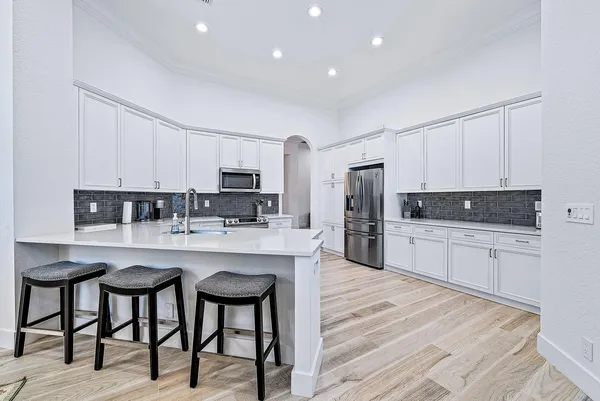 a kitchen with stainless steel appliances granite countertop a table chairs sink refrigerator and cabinets