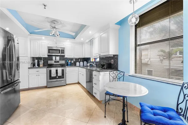a kitchen with stainless steel appliances granite countertop a sink a stove a refrigerator cabinets and a dining table