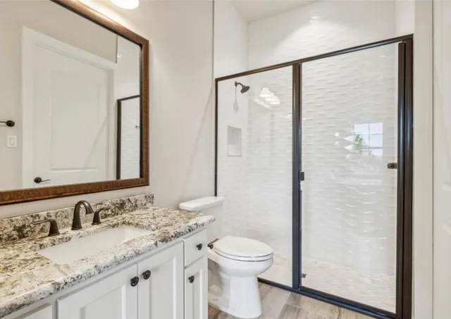 a bathroom with a granite countertop sink toilet and shower