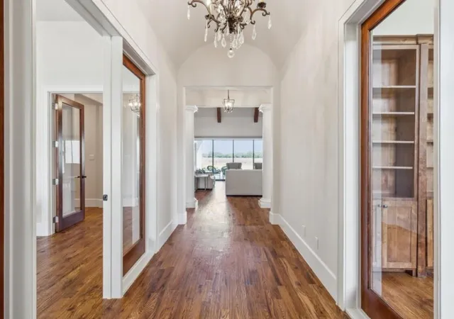 a view of a hallway with wooden floor and a bathroom