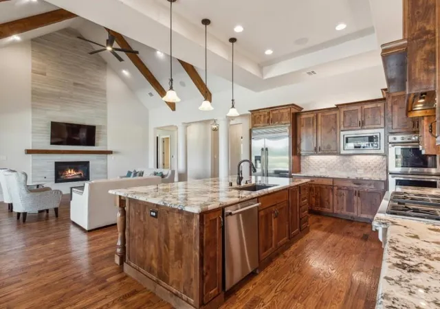 a kitchen with stainless steel appliances kitchen island granite countertop a stove a sink and a wooden floors