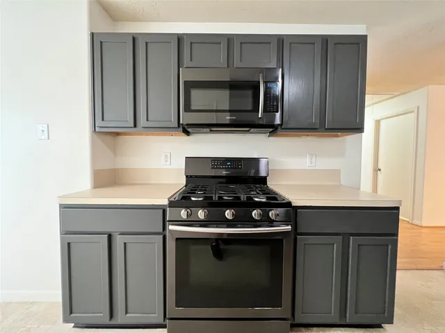 a kitchen with stainless steel appliances a stove a microwave and sink