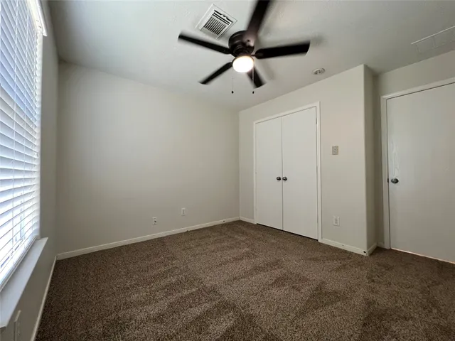 an empty room with a ceiling fan and window