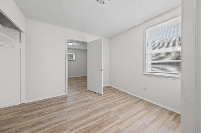 a view of an empty room with wooden floor and a window