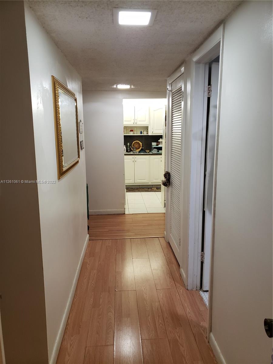 Cypress Bend Pompano Beach, FL 33069 - Photo 12 of 31 a view of a hallway to an empty room with wooden floor and a kitchen