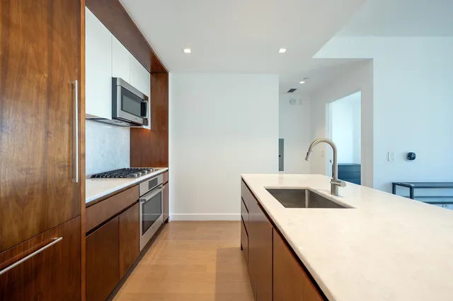 a kitchen with stainless steel appliances granite countertop a sink and a stove top oven with wooden floor