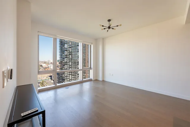 an empty room with wooden floor fan and windows
