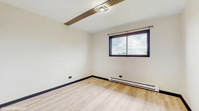 a view of empty room with wooden floor and fan