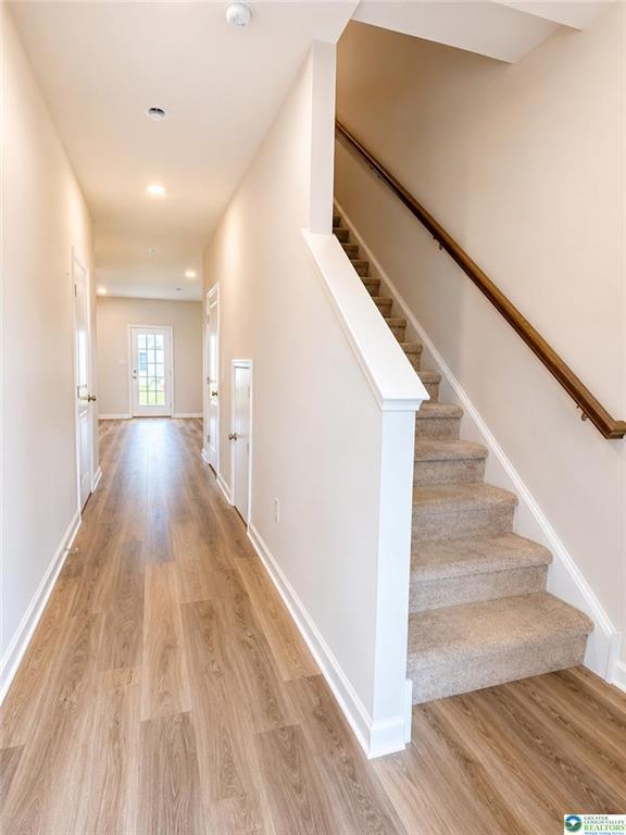 Smooth wood floors guide the way past carpeted stairs to a back glass door.