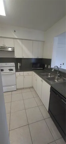 a kitchen with granite countertop a sink a stove and cabinets