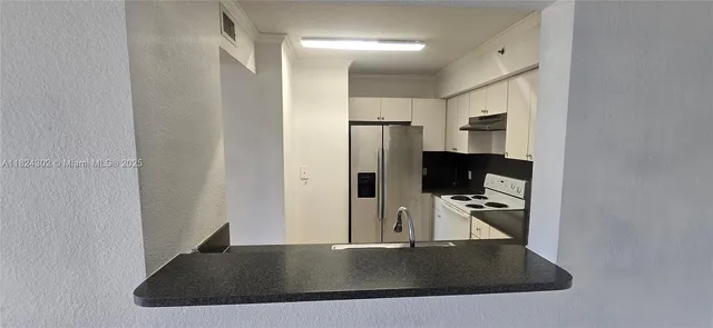 a view of a refrigerator in kitchen and a window