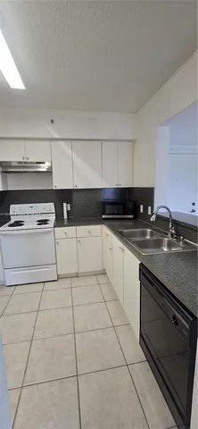 a kitchen with granite countertop a stove top oven and cabinets