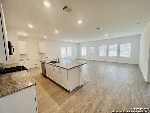 32141 Morels Avenue Bulverde, TX 78163 - Photo 5 of 22 a large white kitchen with wooden floors and stainless steel appliances