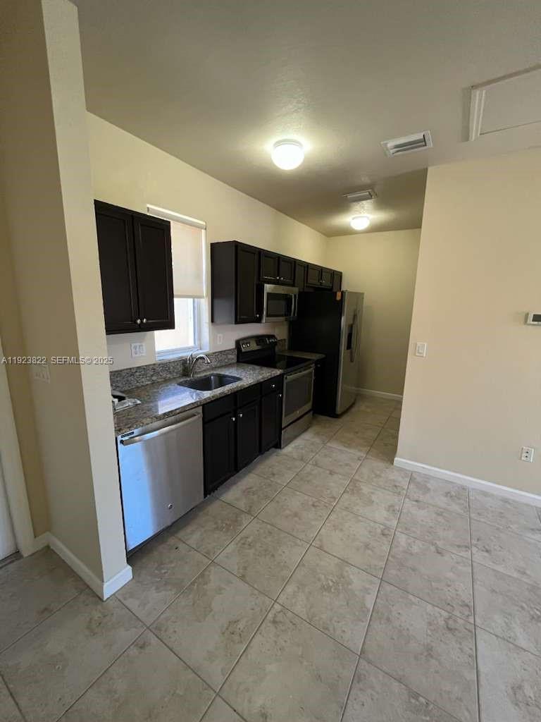 9401 Southwest 172nd Avenue, Unit STUDIO Miami, FL 33196 - Photo 7 of 12 a kitchen with stainless steel appliances a stove a sink a microwave a counter top space and cabinets