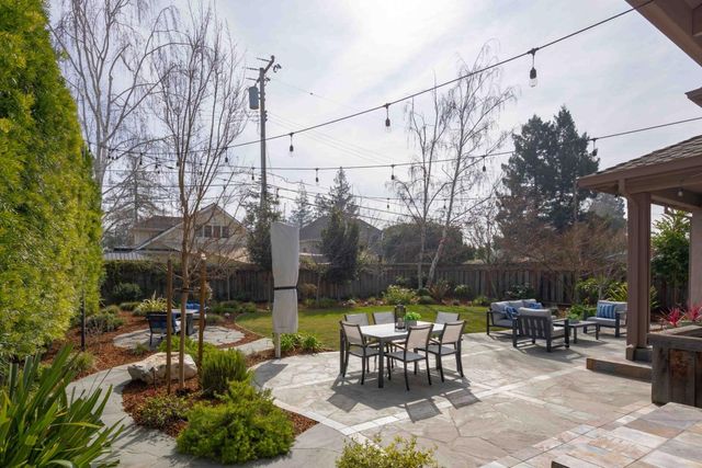 a view of a patio with table and chairs potted plants and large tree