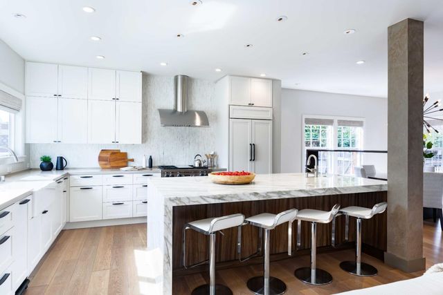 a kitchen with stainless steel appliances kitchen island granite countertop a table chairs sink and cabinets