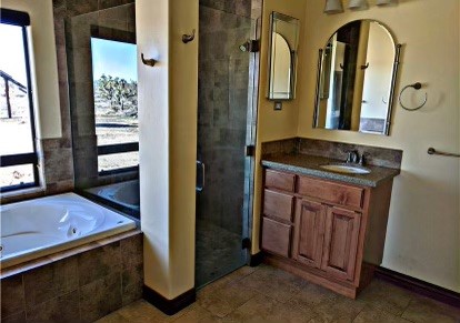 21038 South Cheyenne Road Yucca, AZ 86438 - Photo 39 of 98 Bathroom featuring mirror, a healthy amount of sunlight, dark tile flooring, vanity, and independent shower and bath