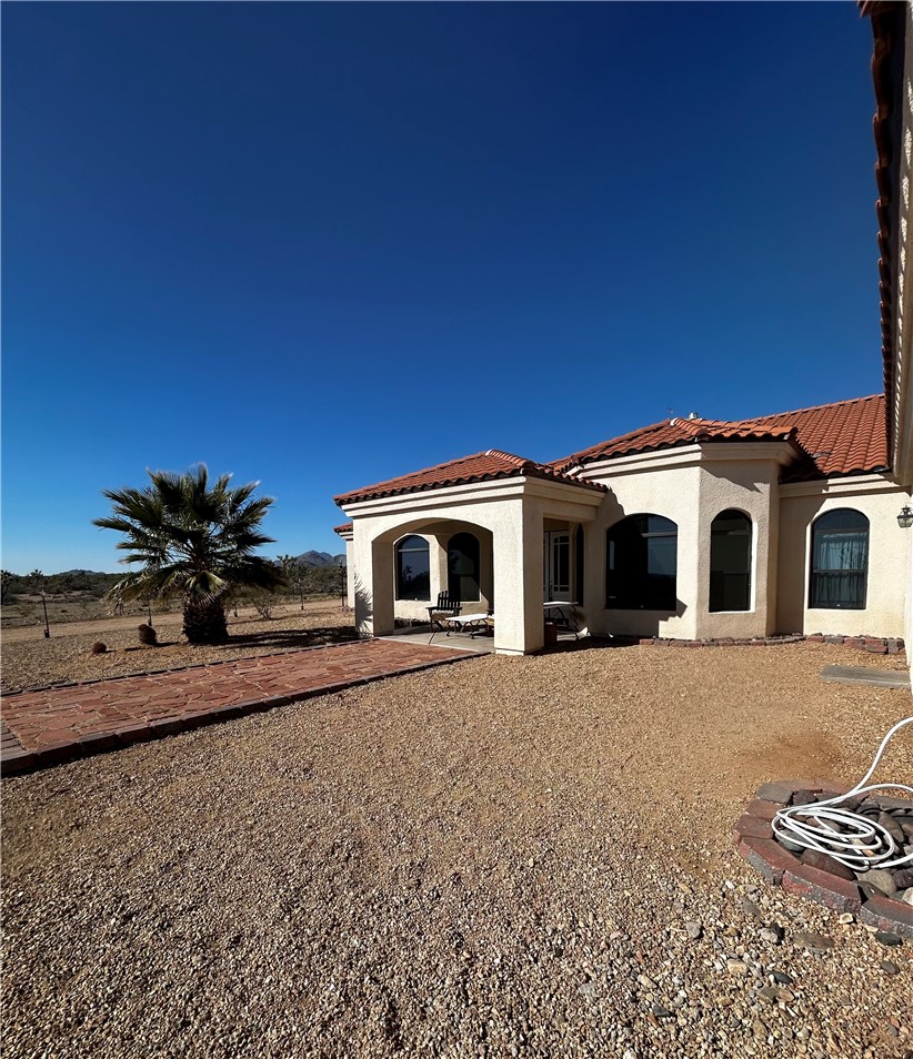 21038 South Cheyenne Road Yucca, AZ 86438 - Photo 5 of 98 Back of house featuring a tile roof, a patio, and stucco siding