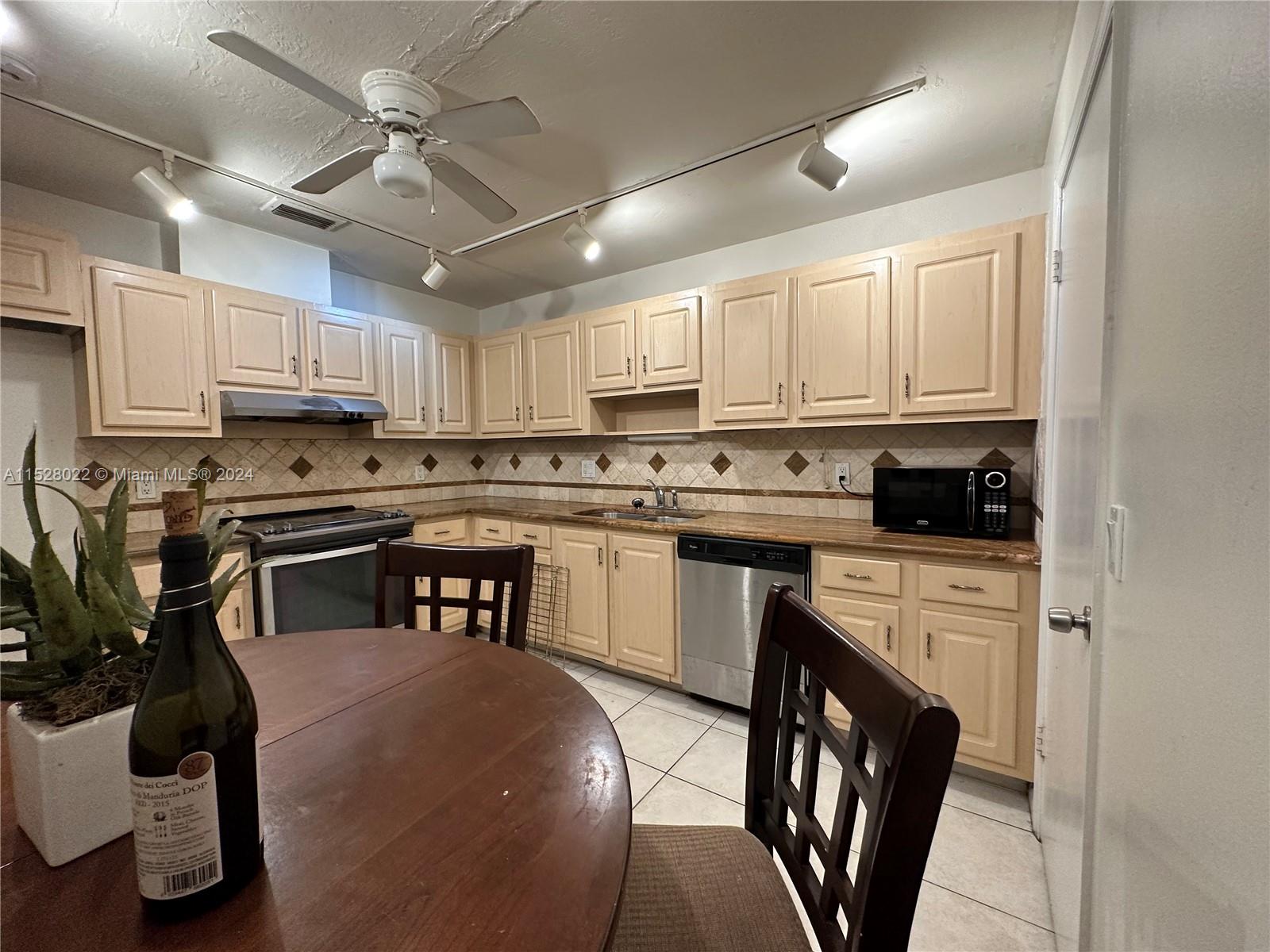 a kitchen with stainless steel appliances granite countertop a stove a sink dishwasher a refrigerator a stove and white cabinets with wooden floor