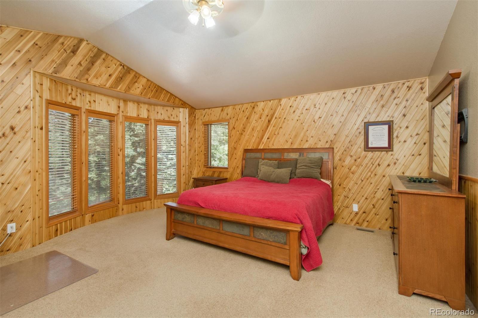 23994 Running Deer Road Conifer, CO 80433 - Photo 14 of 34 a spacious bedroom with a bed and wooden floor