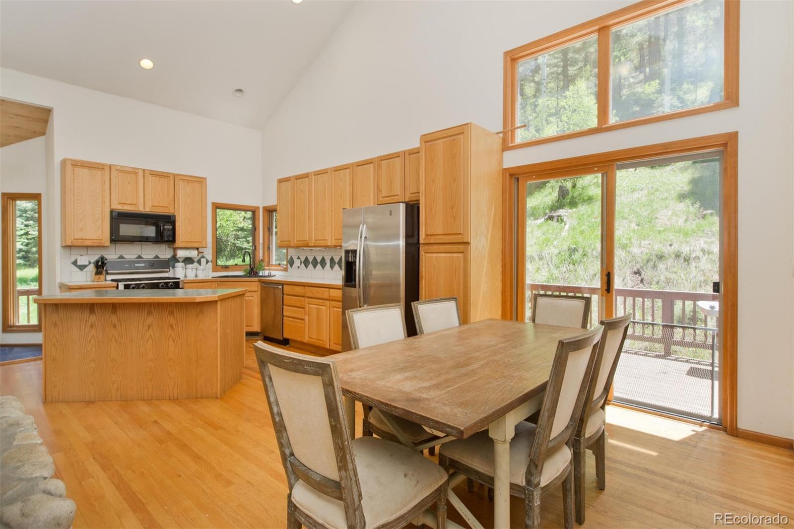 23994 Running Deer Road Conifer, CO 80433 - Photo 8 of 34 a kitchen with a table chairs refrigerator and microwave