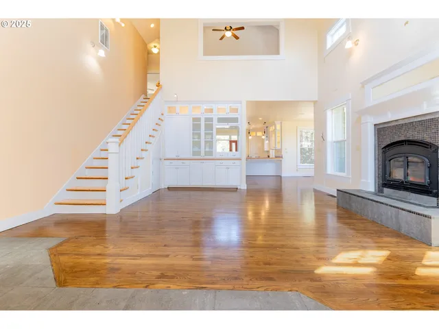 a view of an empty room with wooden floor and a fireplace