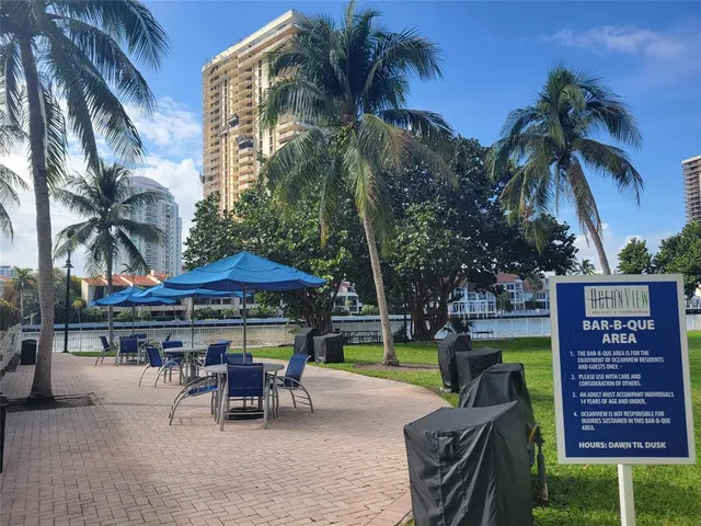 a view of a patio with a table and chairs under an umbrella with palm trees