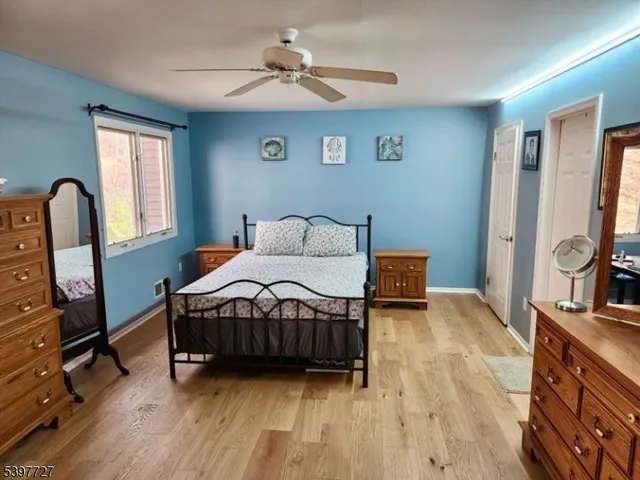 a bedroom with a bed a dresser and wooden floor