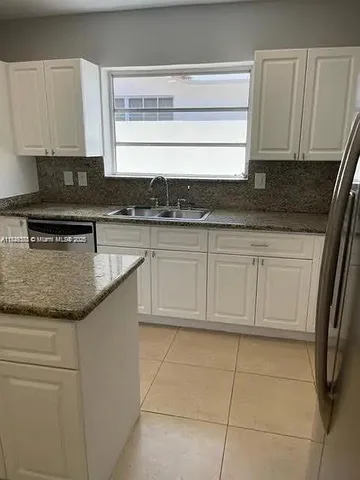 a kitchen with granite countertop a sink a stove and cabinets