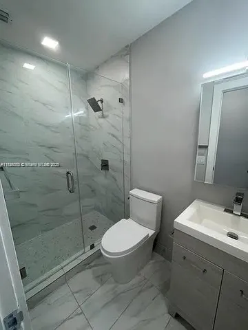 a bathroom with a toilet a sink a mirror and shower