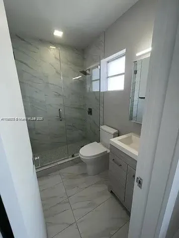a bathroom with a granite countertop shower a toilet and a sink
