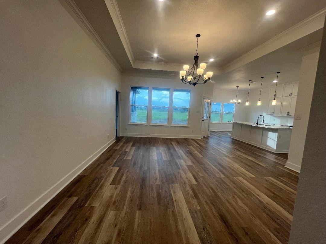 33416 FM 521 Road Angleton, TX 77515 - Photo 4 of 21 This spacious, open-concept living area features elegant medium gray/wood water proof plank flooring, a modern chandelier, and abundant natural light from large windows. The adjacent kitchen boasts stylish pendant lighting and a sleek island perfect for entertaining.