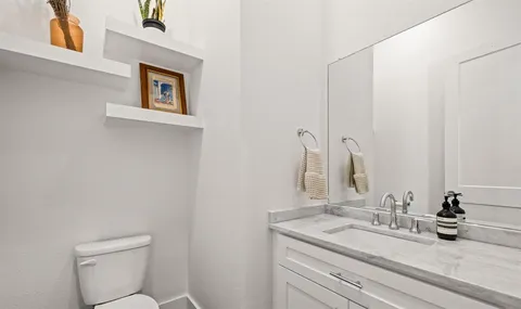 a bathroom with a granite countertop sink a toilet and a mirror