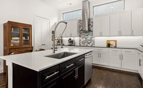 a kitchen with a sink dishwasher and white cabinets with wooden floor