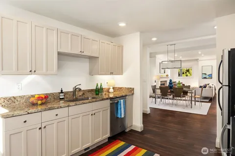 a kitchen with stainless steel appliances granite countertop a refrigerator a stove a sink dishwasher and white cabinets with wooden floor