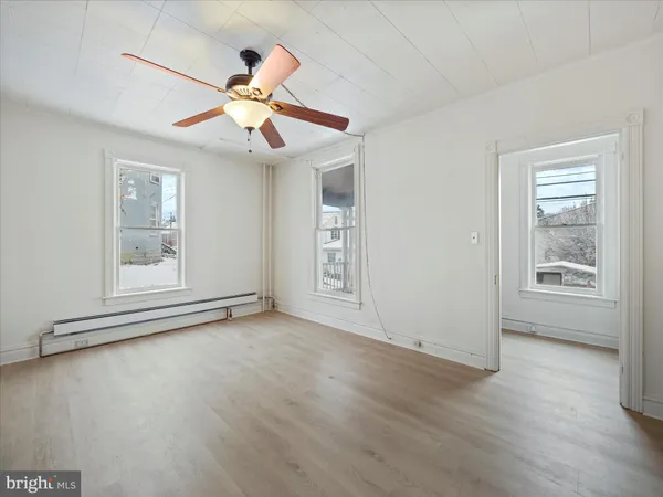 a view of an empty room with window and wooden floor
