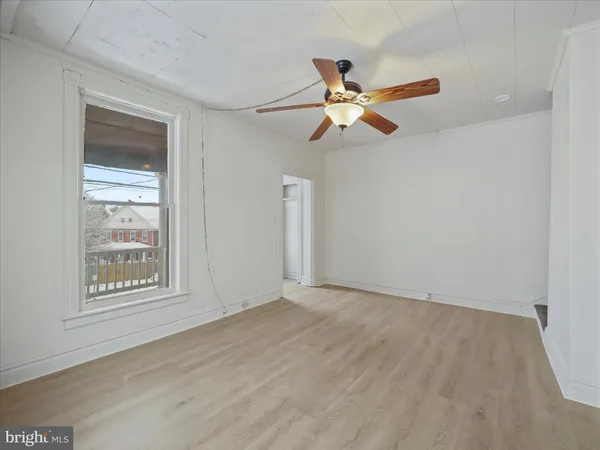 an empty room with windows and fan