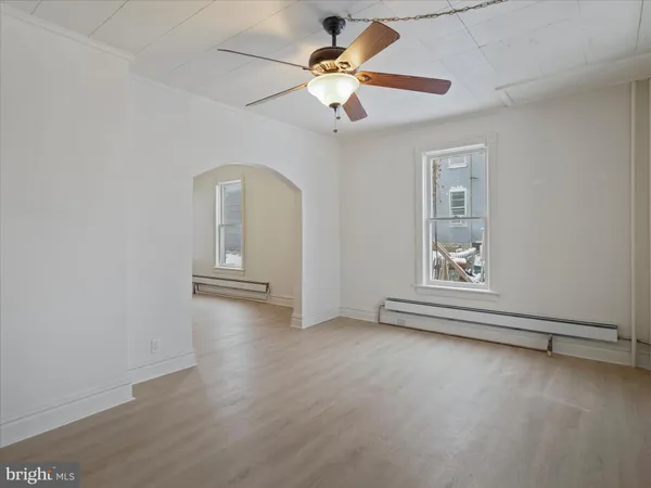 an empty room with wooden floor chandelier fan and windows
