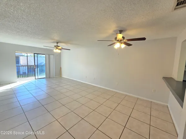 a view of an empty room and chandelier fan
