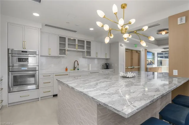 a kitchen with stainless steel appliances granite countertop a sink a oven and a white cabinets