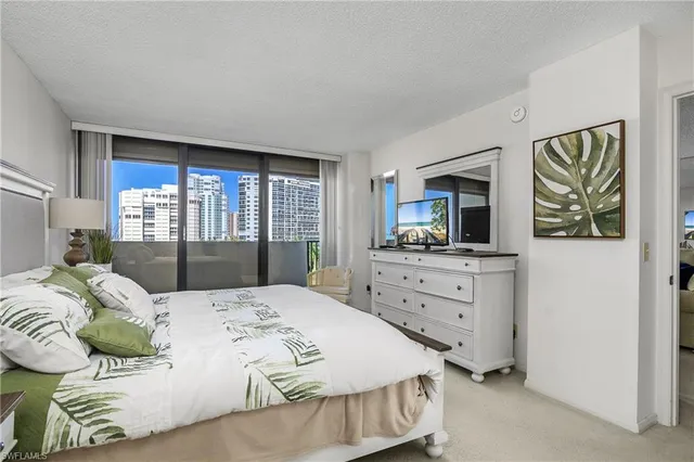 a bedroom with a large bed and a flat tv screen on dresser
