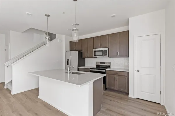 a kitchen with stainless steel appliances granite countertop a sink a stove a refrigerator cabinets and wooden floor