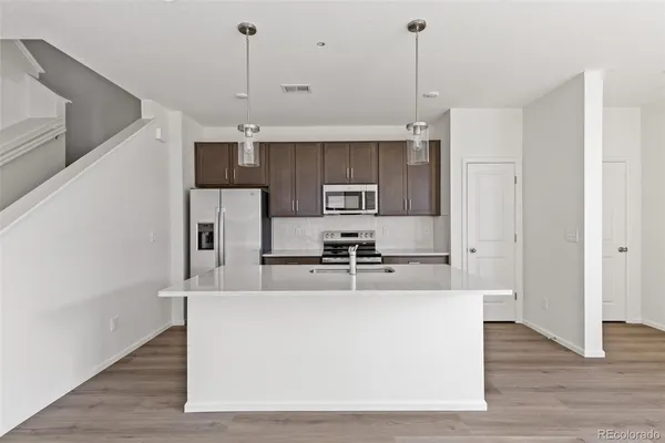 a large kitchen with kitchen island a stove a sink a center island and wooden floor