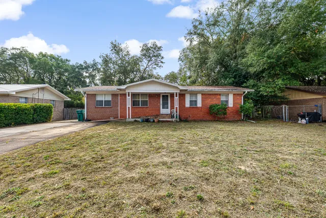 a front view of a house with a garden and trees
