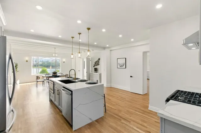 a kitchen with stainless steel appliances granite countertop a sink a stove and a wooden floors