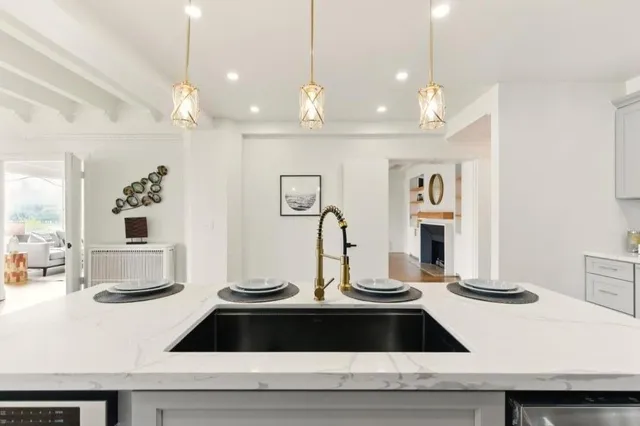 a kitchen with stainless steel appliances granite countertop a stove top oven a sink dishwasher a refrigerator and a dining table with wooden floor